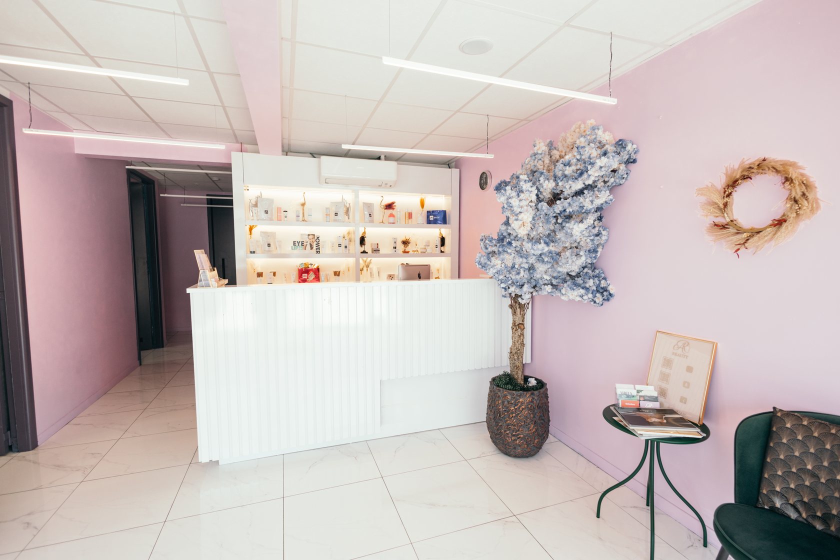 Beauty salon reception with pink walls, white counter, product shelves and flowers