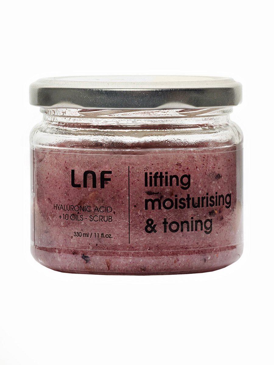Glass jar of purple body scrub with a silver lid on a white background