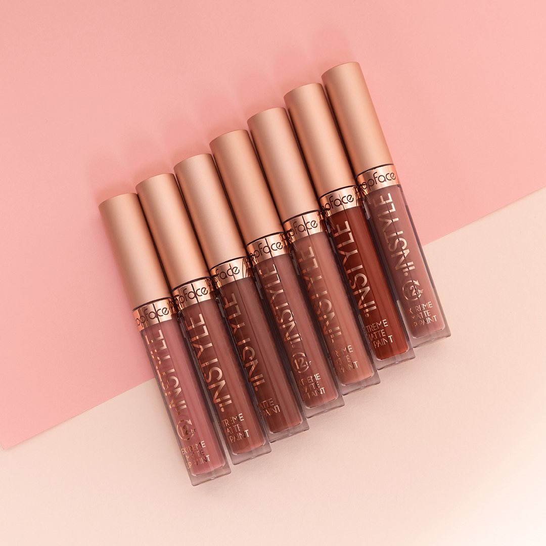 Seven matte lip paint tubes arranged diagonally on a pink and cream background