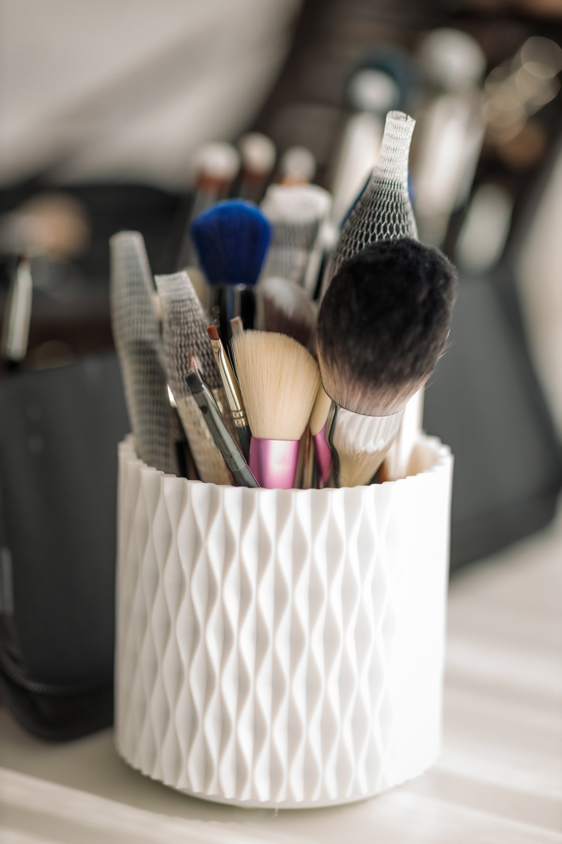 Make-up artist's brushes in a white textured holder, softly lit