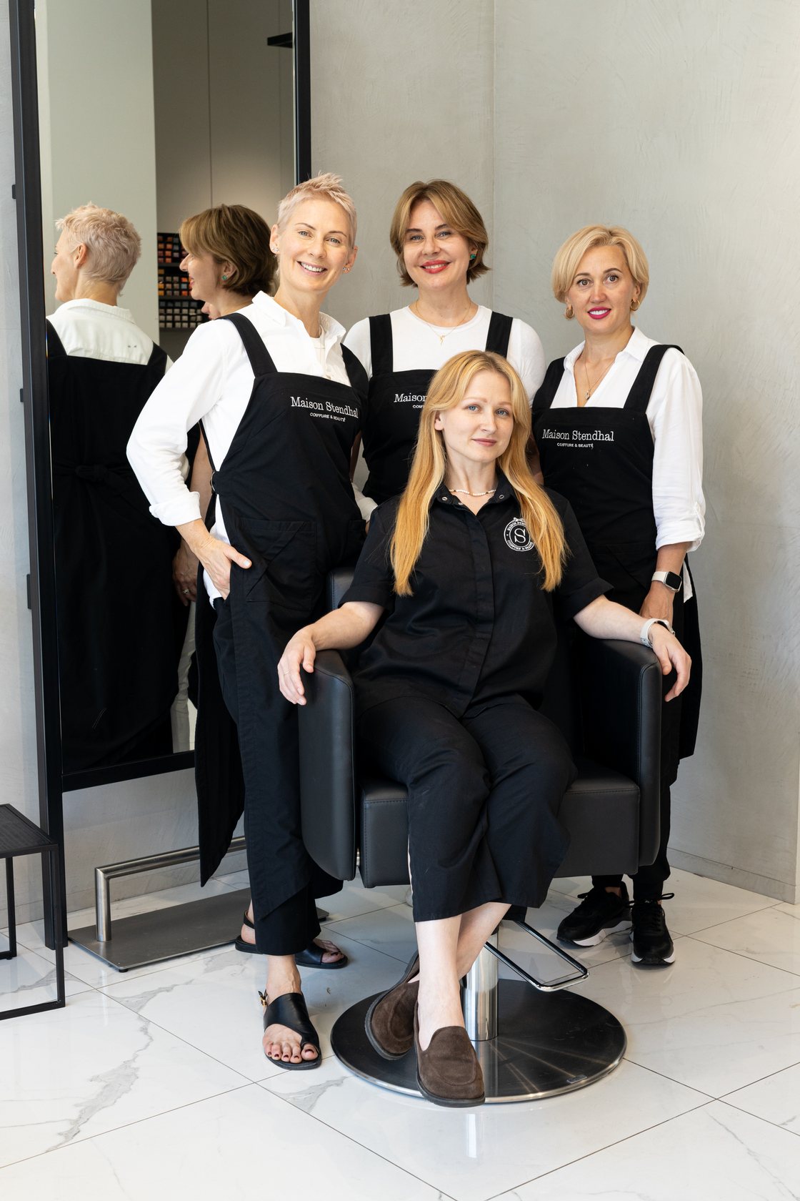Team portrait of four beauty salon staff in black uniforms in their Brussels salon